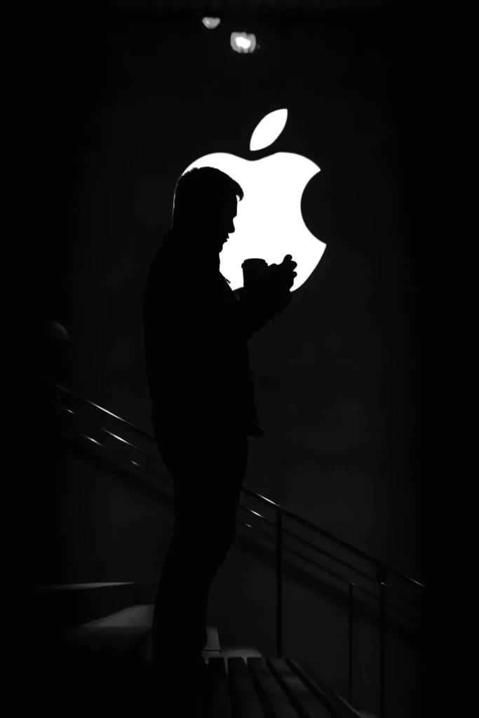 this image is showing half apple logo and a man stands up on the stairs in front of apple logo